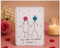 A handmade white greeting card with a black stitched border, featuring a minimalist stick figure couple with pink and blue buttons for heads, surrounded by small red hearts. The card reads 'YOU ARE MY HAPPY PLACE!' in black text.